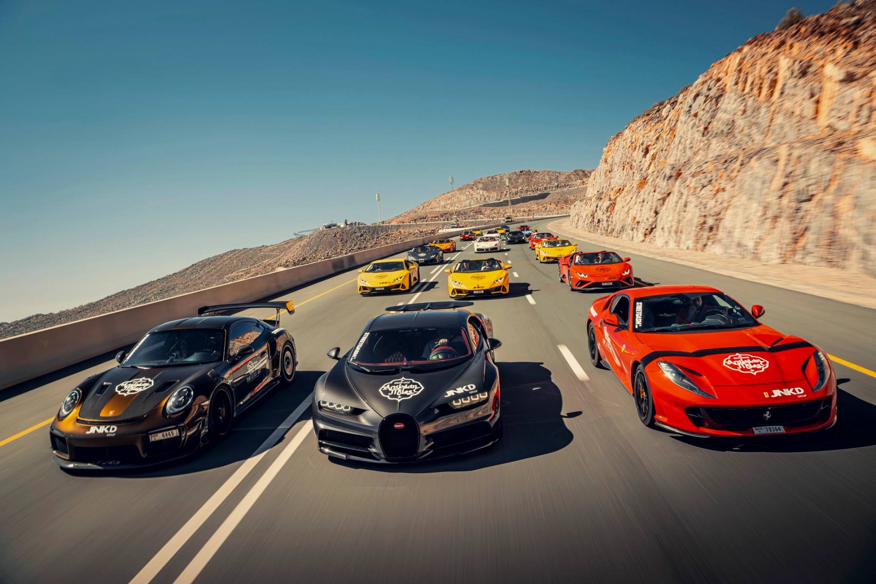 Supercars driving in convoy on an open road during a StreetGasm tour.