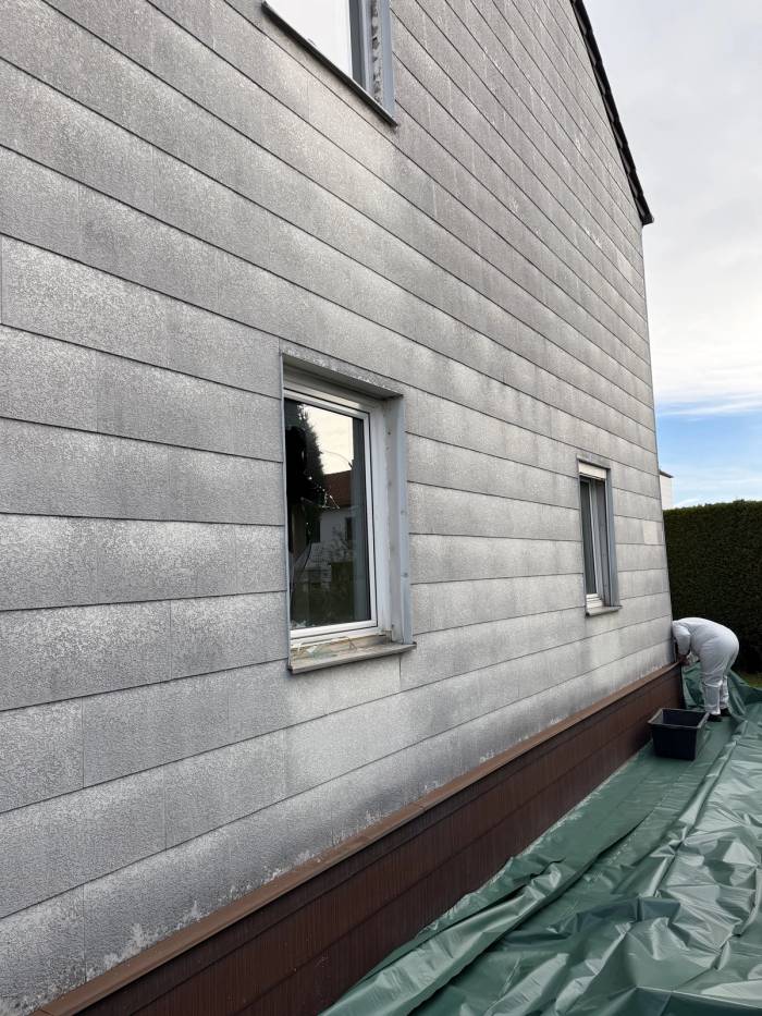 Fassade eines Wohngebäudes während Sanierungsarbeiten mit Absicherung am Dachrand