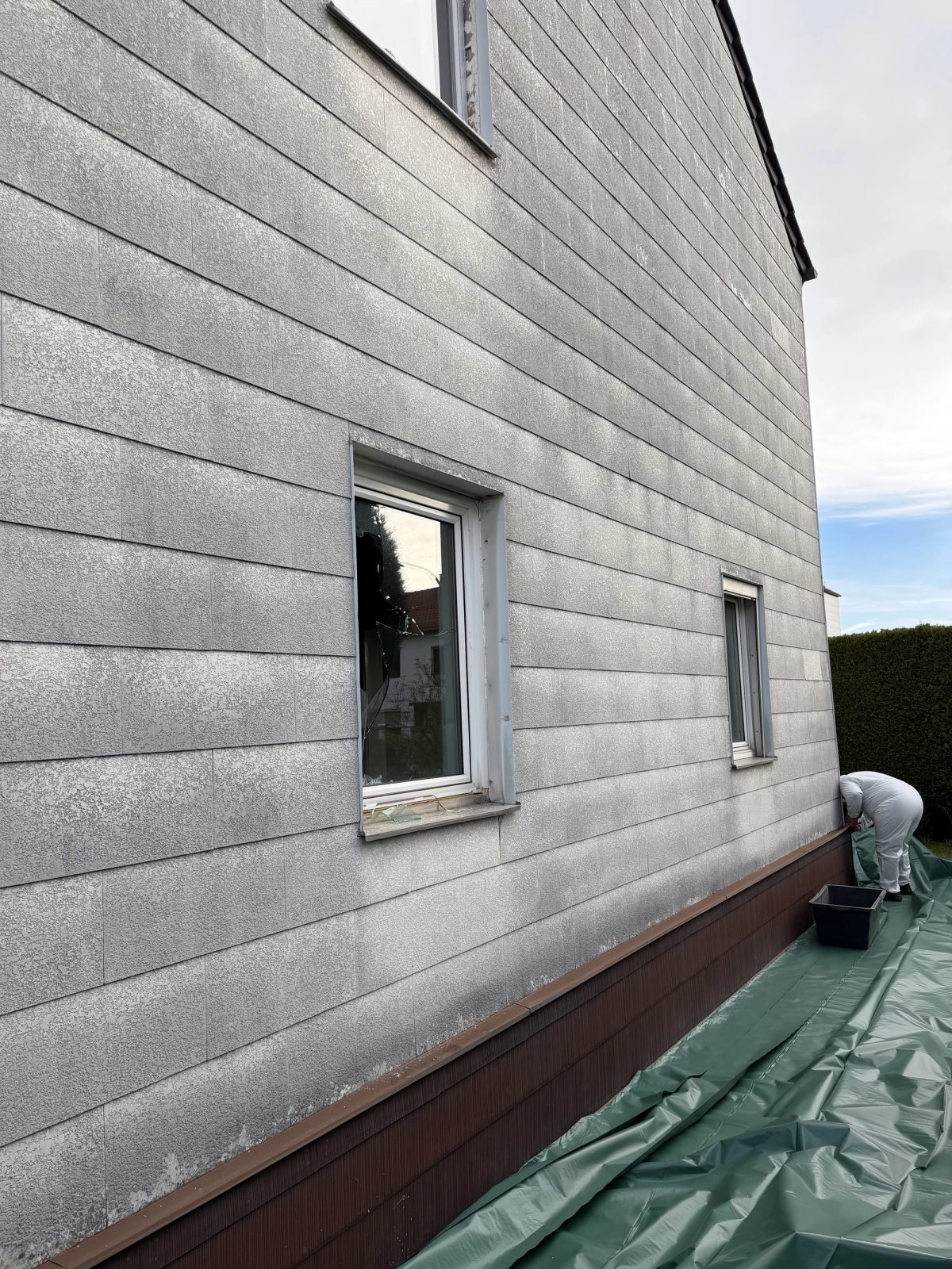 Bestandsgebäude in Ingolstadt mit asbesthaltigen Fassadenplatten vor Beginn der Sanierung — komplette Fassade mit Holzsockel