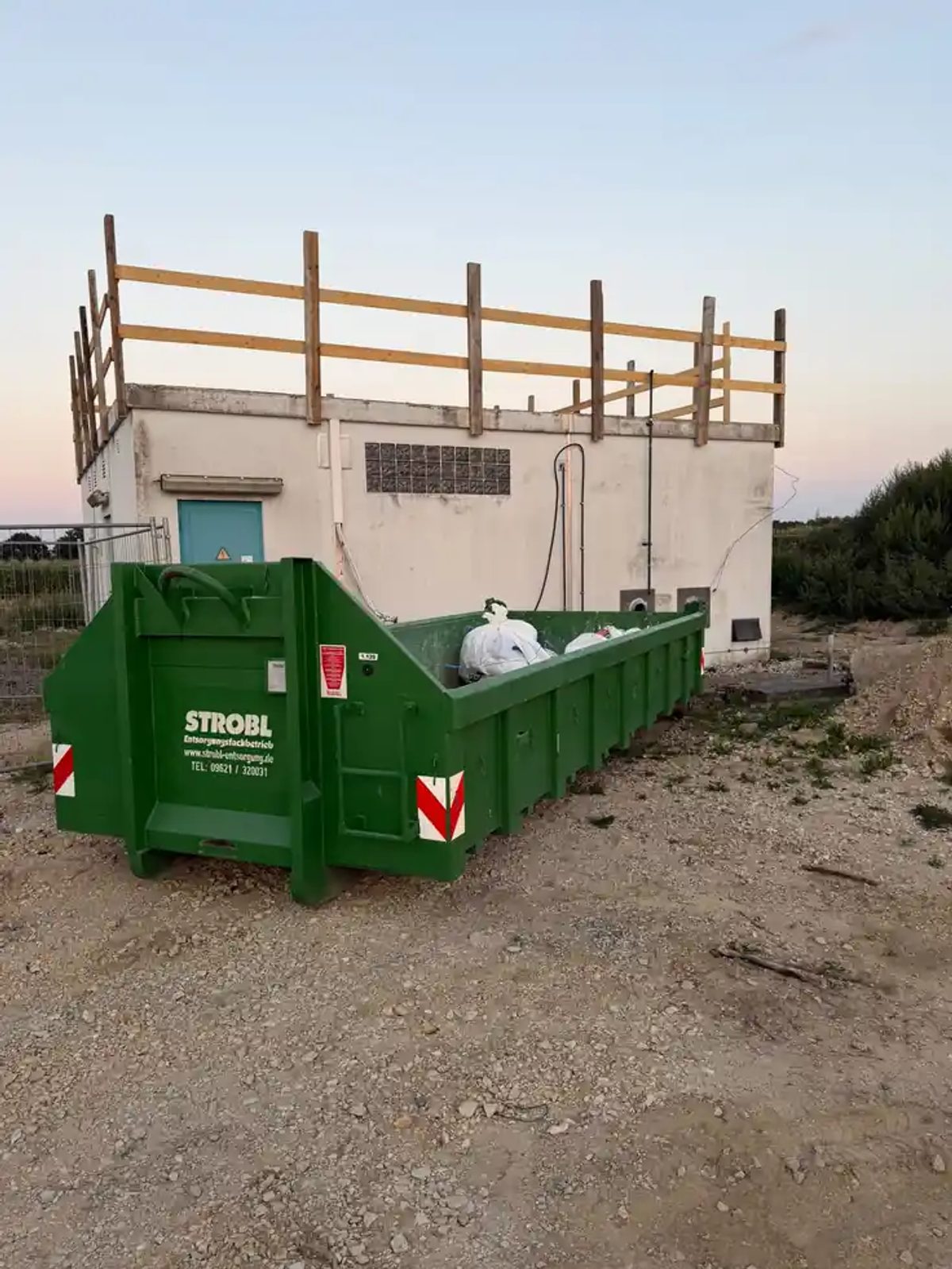 Abrollcontainer mit staubdicht verpackten Big Bags voller asbesthaltiger Dachabdichtung zur Entsorgung als gefährlicher Abfall
