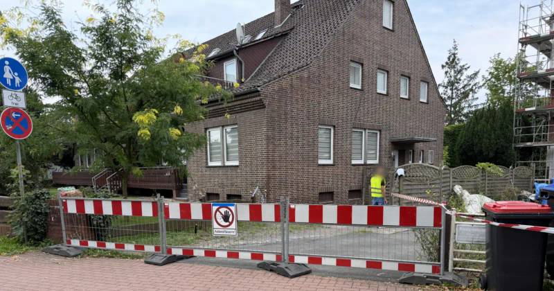 Asbest-Abriss in der Nachbarschaft: abgesperrte Baustelle in einer Wohnstraße mit Warnschild Asbestfasern vor dem Wohnhaus