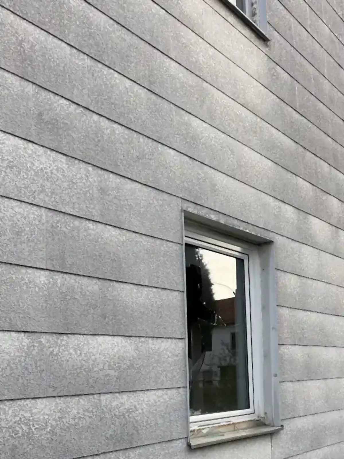 Nahaufnahme einer grauen Asbestzementplatte mit sichtbarer Faserstruktur an der Oberfläche