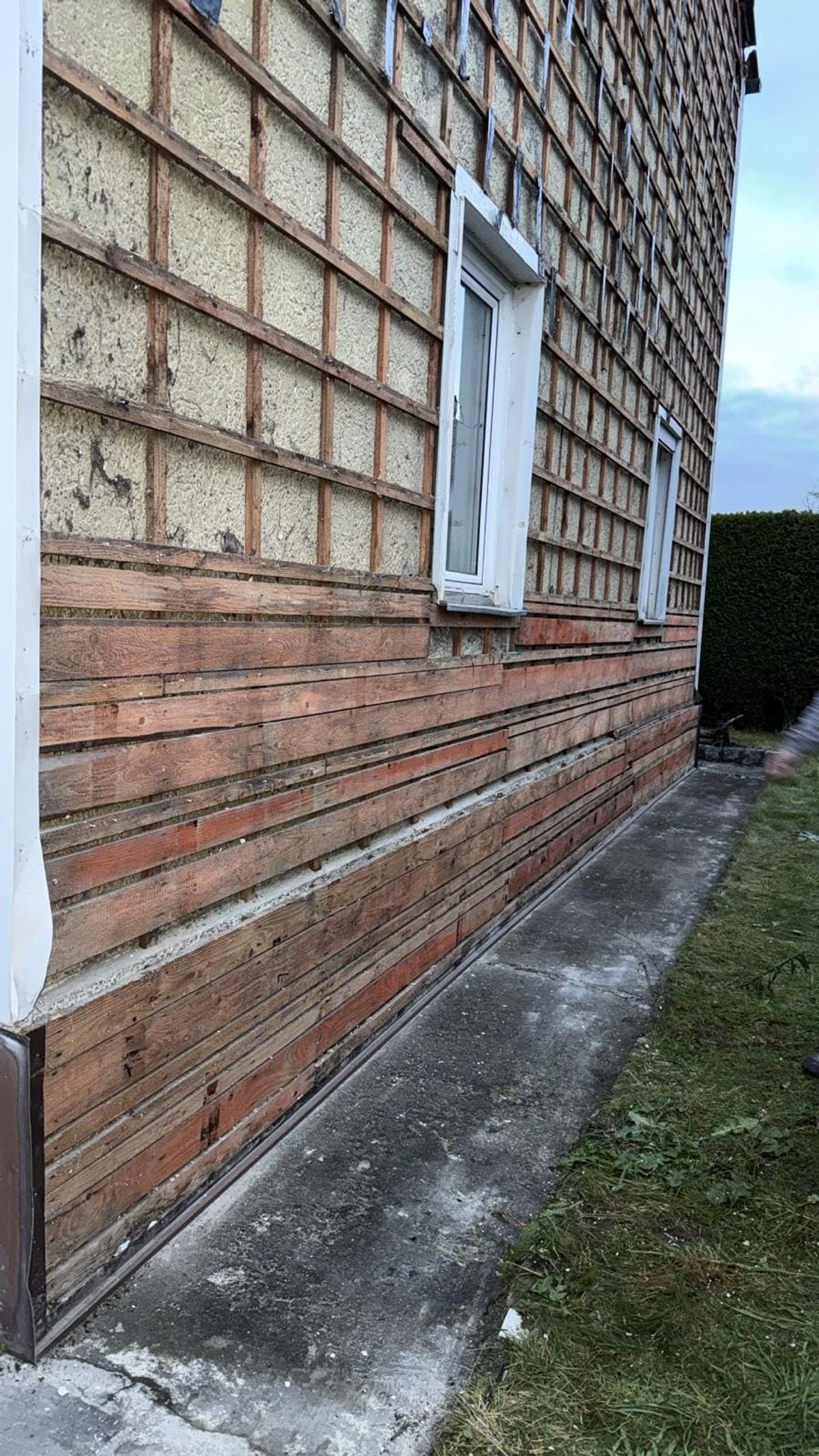 Seitenansicht des Bestandsgebäudes in Ingolstadt mit asbesthaltigen Fassadenplatten, Holzsockel und Fensterreihen