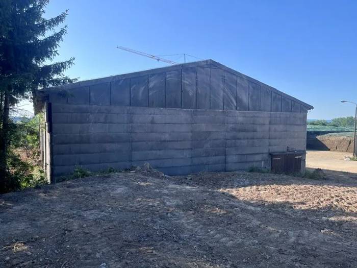 Eternitplatten erkennen: großformatige graue Faserzementplatten an der Giebelwand einer Halle vor der Sanierung.