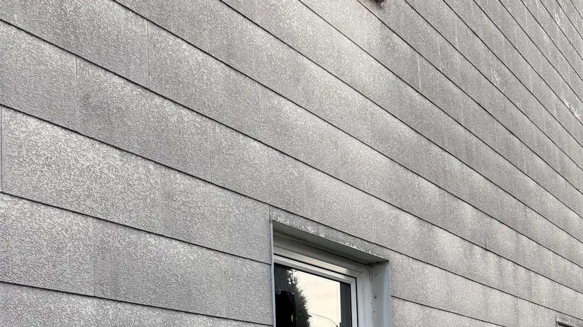 Graue Asbestzement-Fassadenplatten an einem Altbau – optisch nicht von asbestfreiem Faserzement unterscheidbar