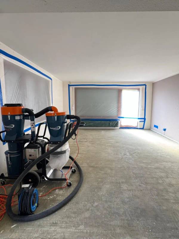 Kernsanierung in Oberursel: H-Entstauber mit Vorabscheider im Arbeitsbereich, Fenster mit Folie abgeklebt, Estrich mit Kleberbett