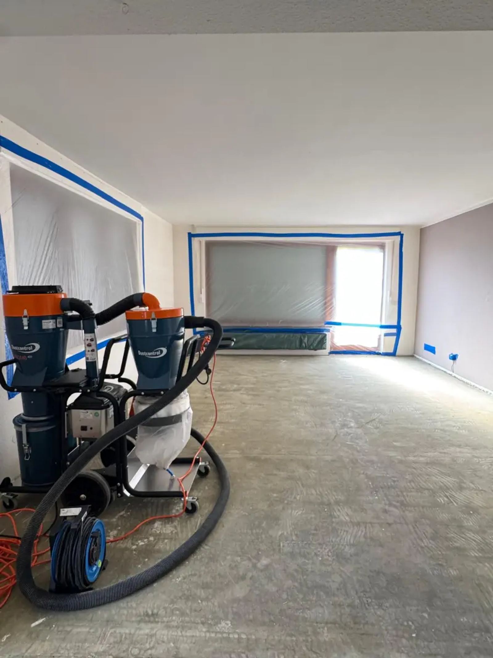 Kernsanierung in Oberursel: H-Entstauber mit Vorabscheider im Arbeitsbereich, Fenster mit Folie abgeklebt, Estrich mit Kleberbett