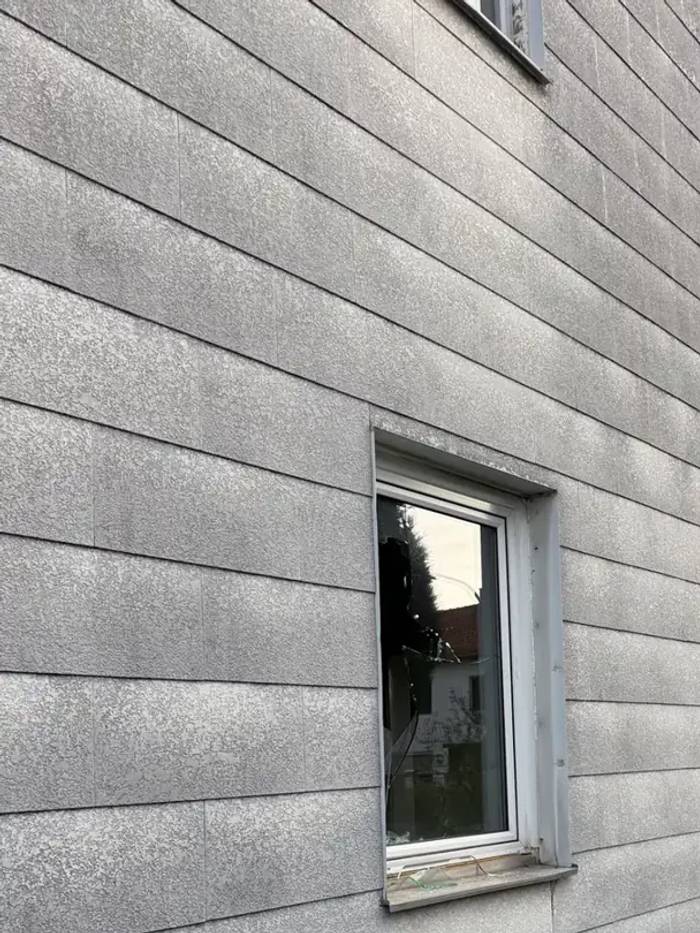 Graue Asbestzement-Fassadenplatten an einem Wohnhaus – festgebundene Faserzement-Verkleidung mit Fenster.