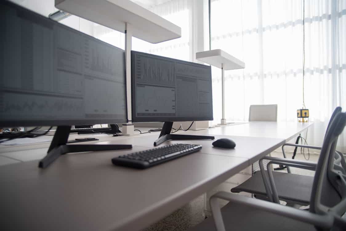 photo of workspace with two monitors and keyboard on table