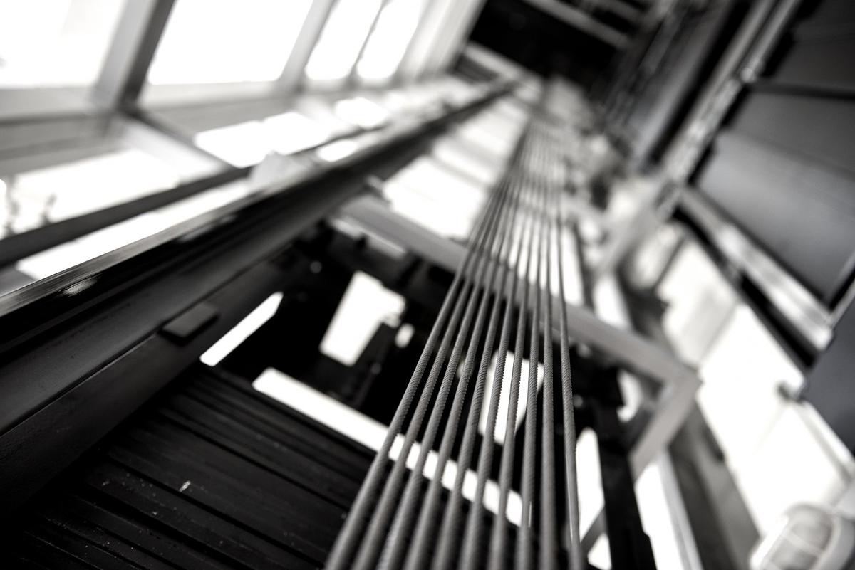 Close-up of suspension ropes and guide rails inside an elevator shaft