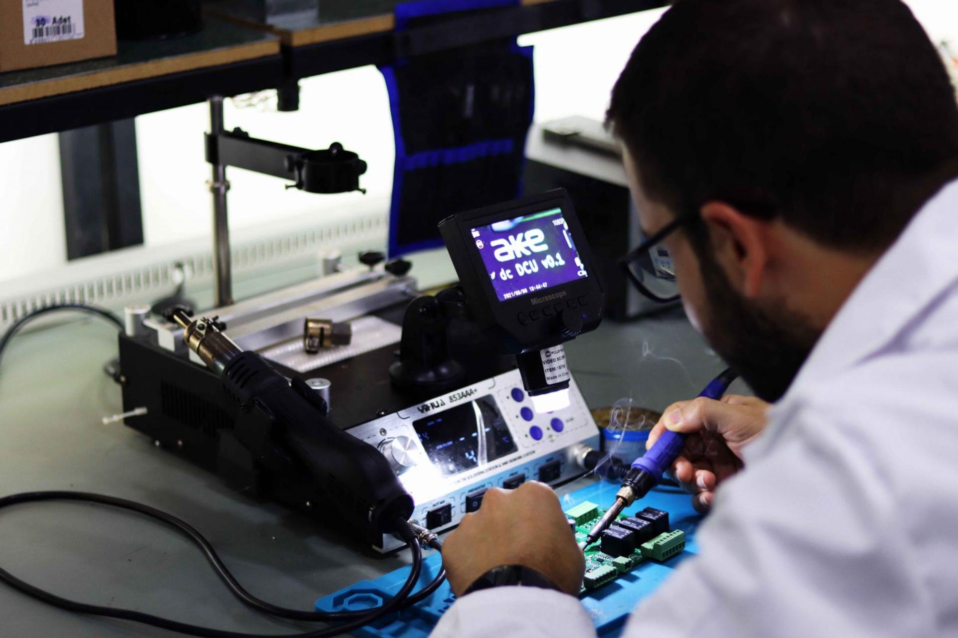 AKE lab technician soldering an electronic board under a digital microscope
