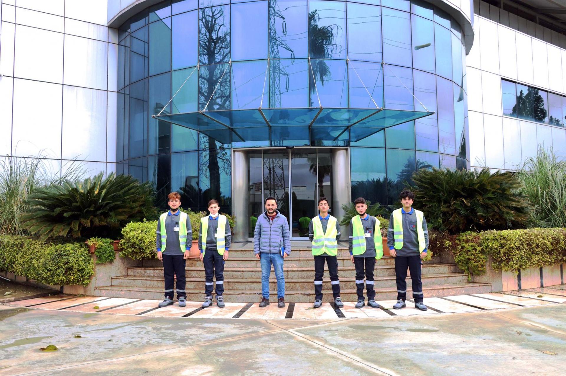 AKE team members in safety vests at the glass entrance of the factory