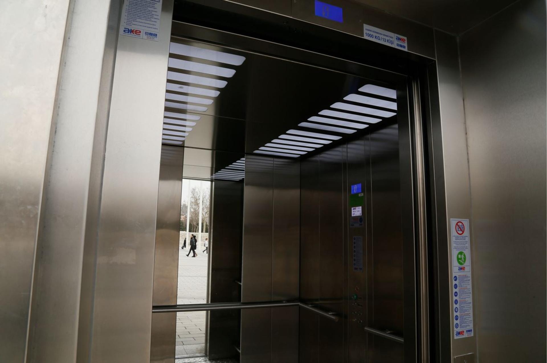 Stainless steel elevator cabin with open door and illuminated ceiling at an outdoor installation