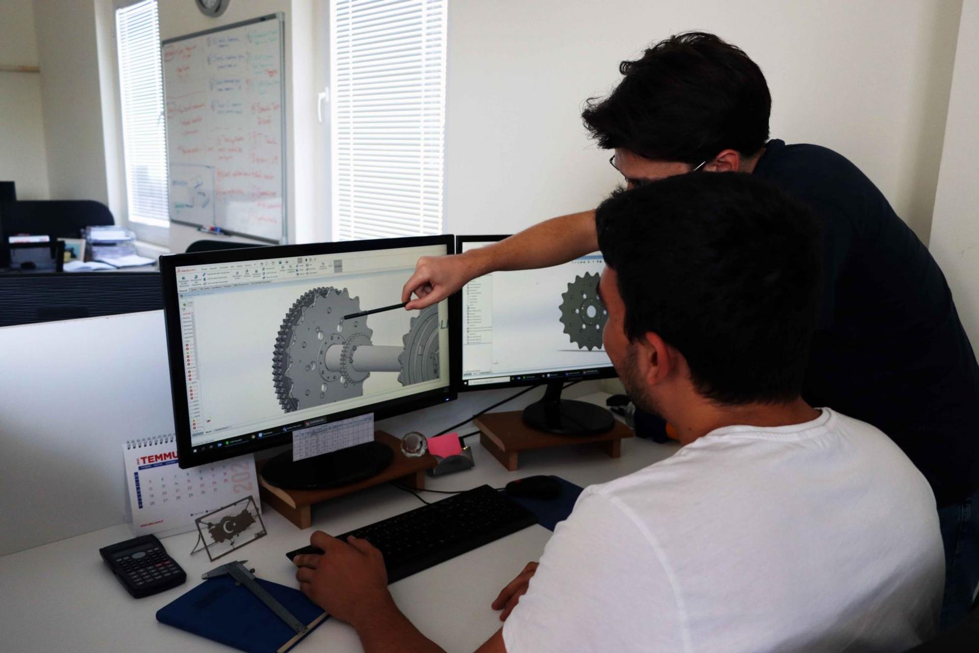 Two AKE engineers reviewing a 3D CAD design on screen in the office