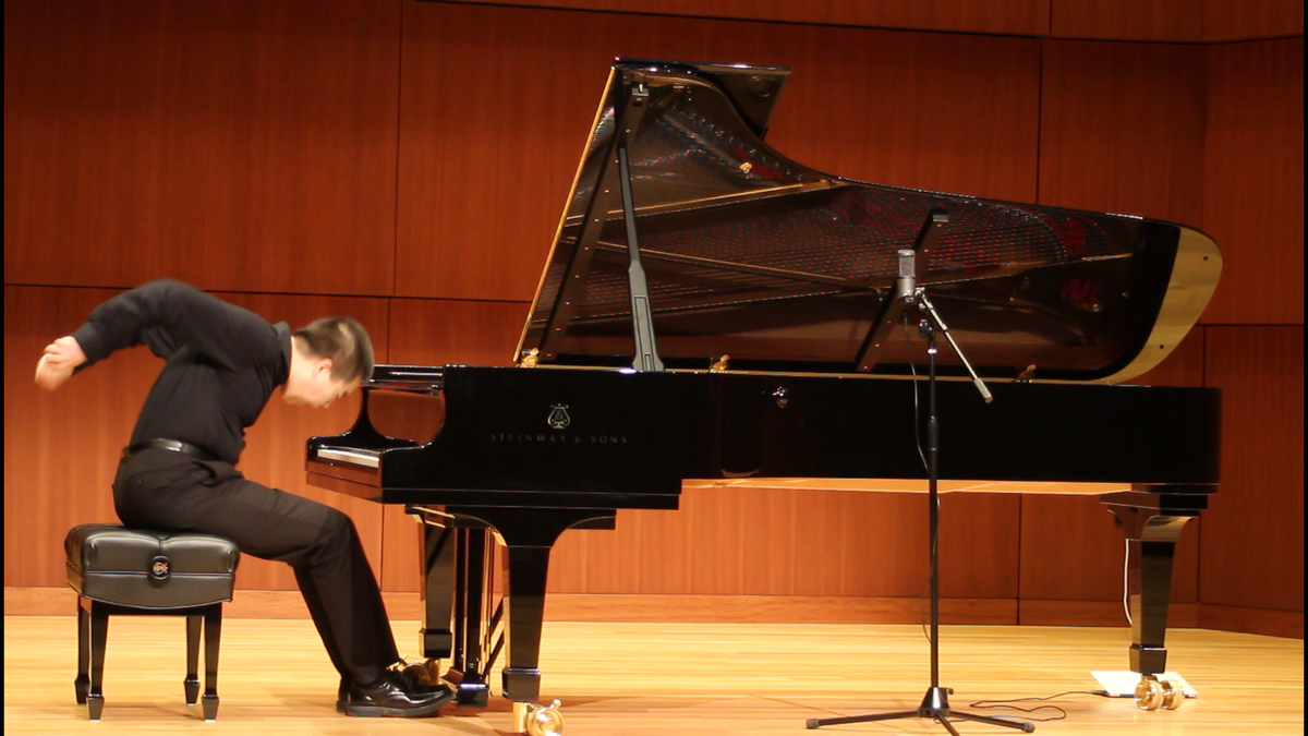 Un pianiste soliste penché vers un piano à queue pendant un récital
