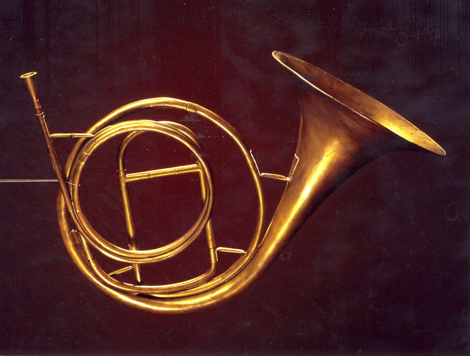 A brass inventionshorn with coiled tubing and a broad bell