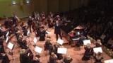 Dois pianistas e uma orquestra se apresentando no palco da Great Amber Concert Hall