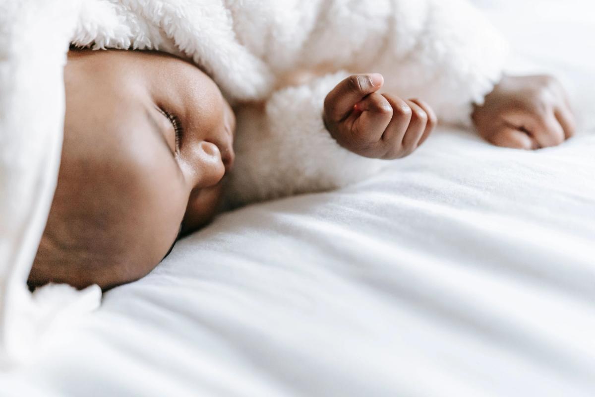 Bebé dormido con ropa suave sobre una manta clara