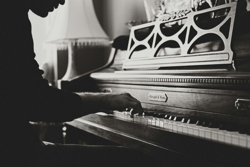 Close-up of hands playing a spinet piano, black and white