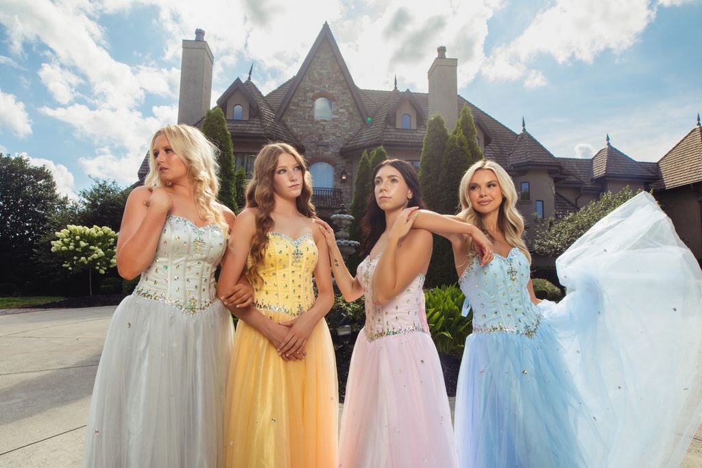 Three models in pastel tulle gowns standing in front of the manor facade.
