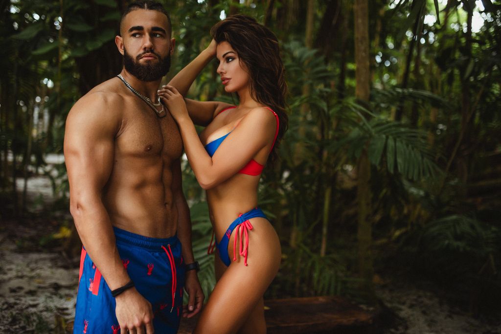 Couple in matching blue swimwear posing together at the edge of the jungle.