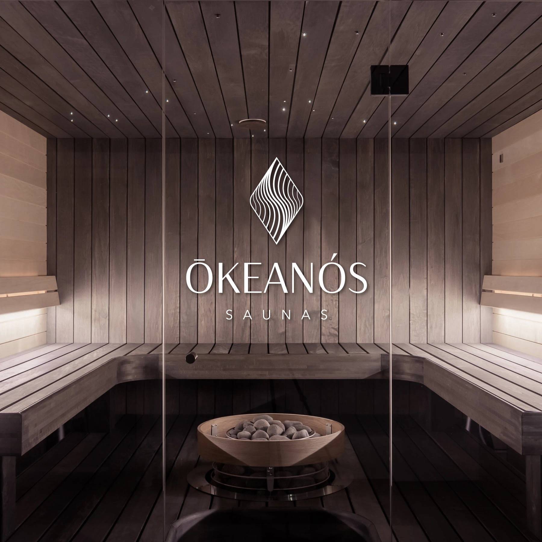 Okeanos Saunas logo mounted on the timber wall of a dark sauna interior.