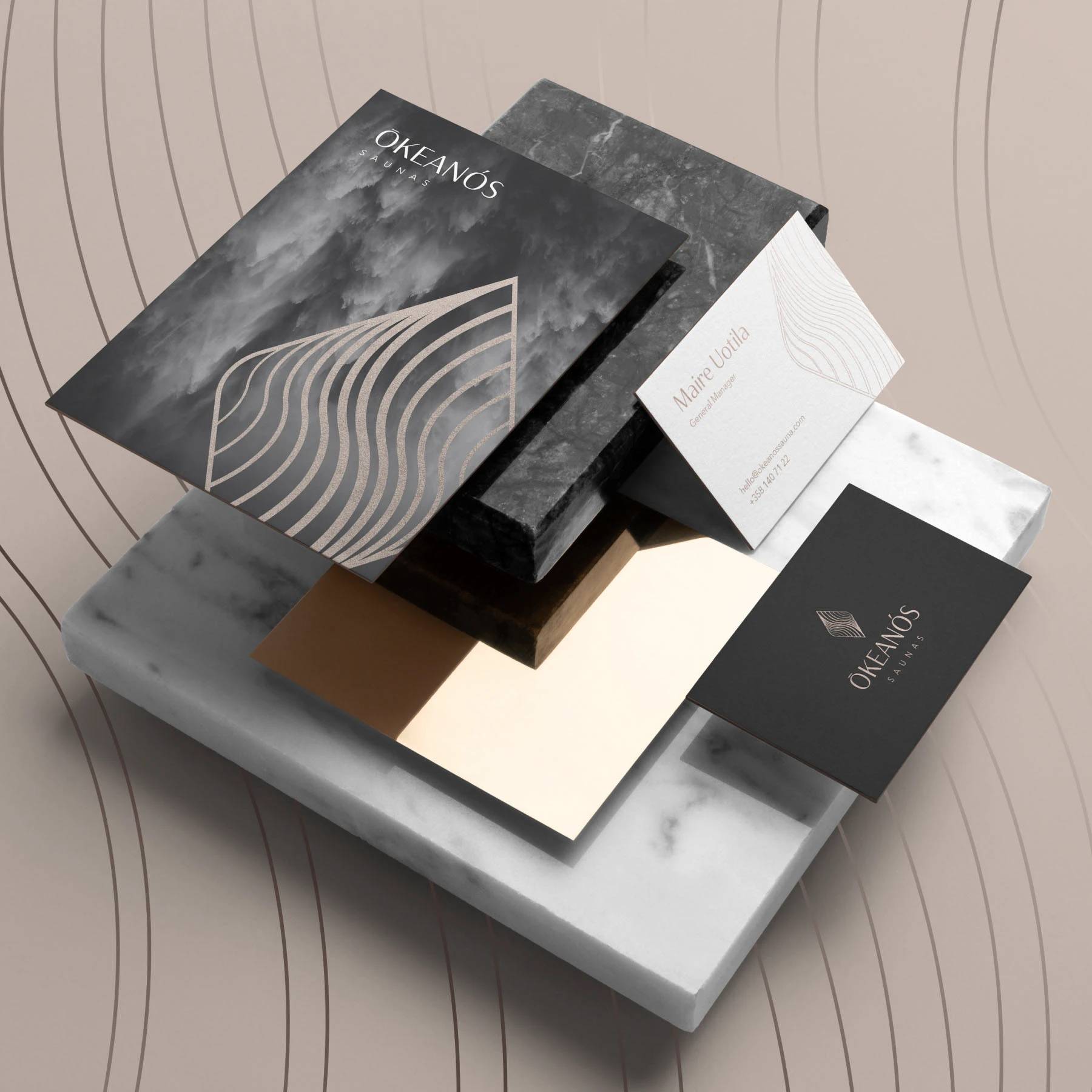 Okeanos Saunas stationery and business cards in charcoal, cream, and bronze.