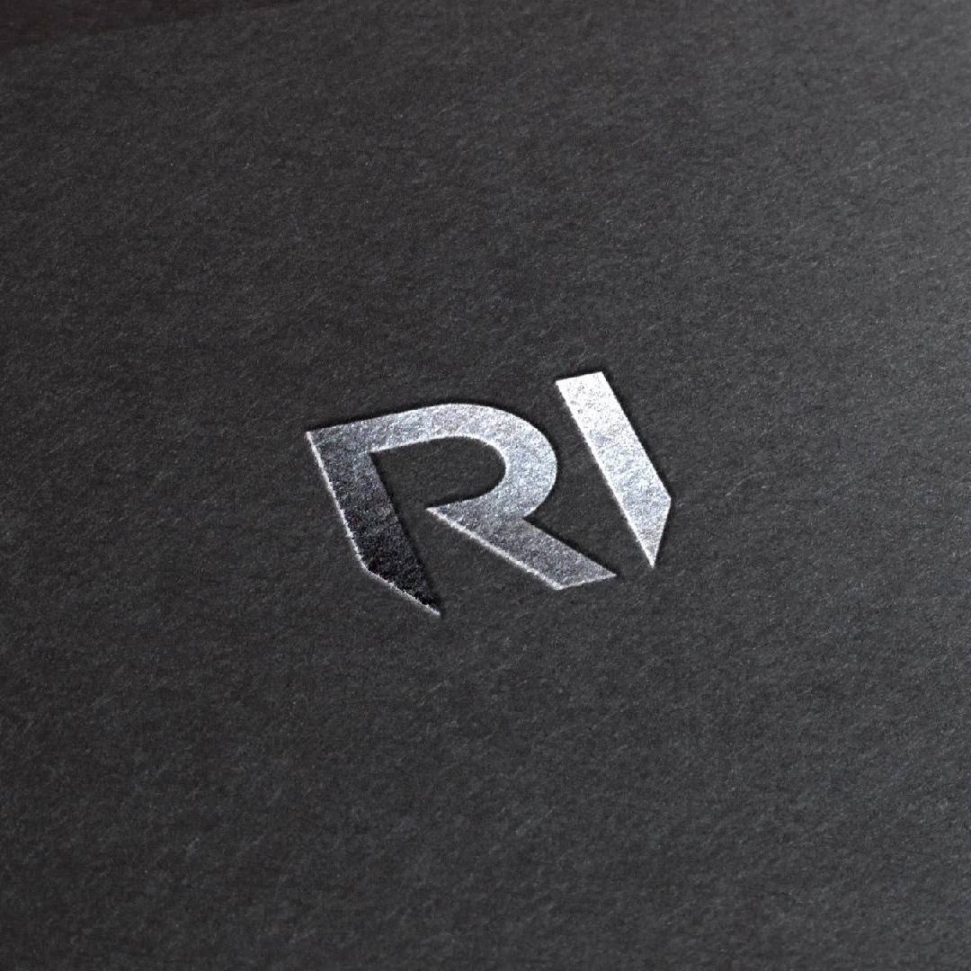 Metallic RotaInox RI monogram embossed on dark textured paper.