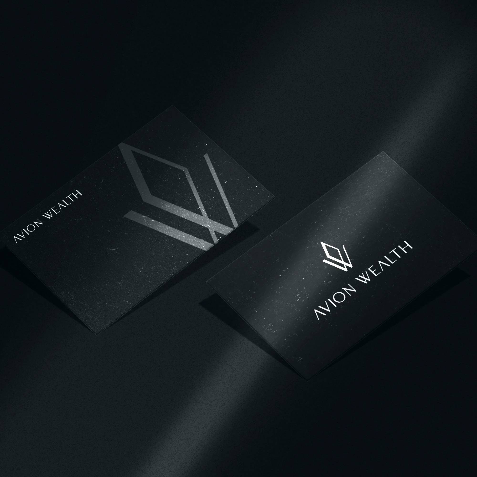 Black Avion Wealth business cards with a silver angular monogram.