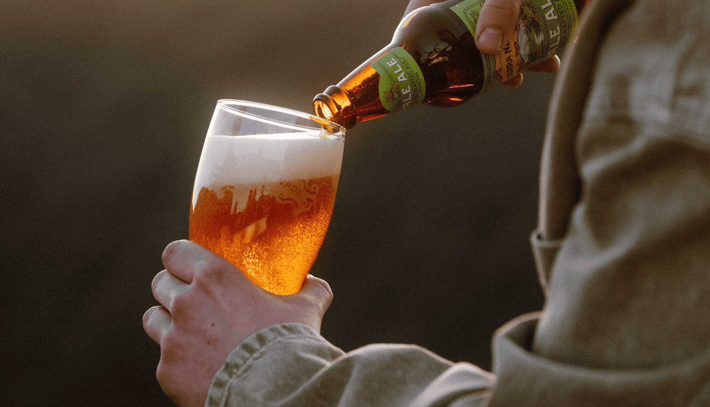 a person pouring a sierra nevada beer into a pint glass