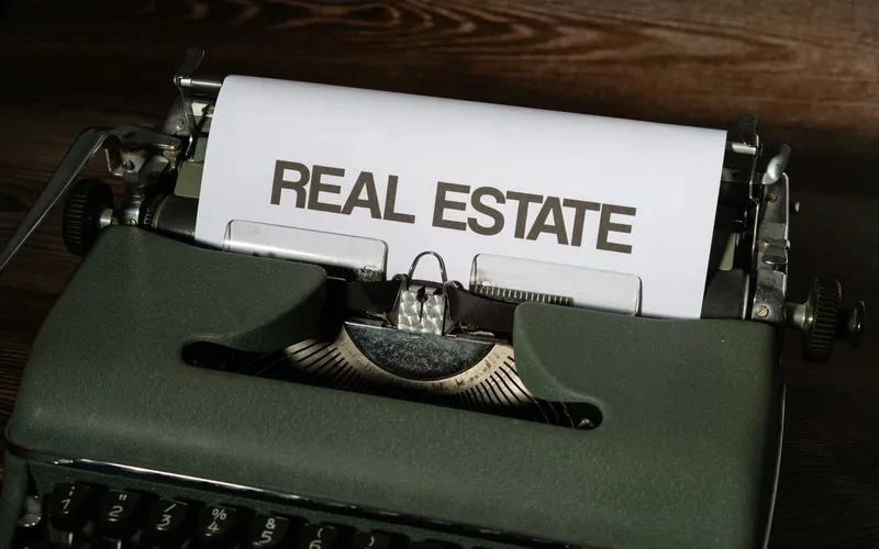 A vintage typewriter with a sheet of paper reading REAL ESTATE