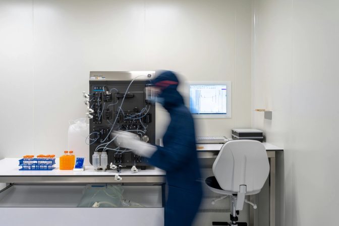 Scientist in a cleanroom suit operating a bioprocess system