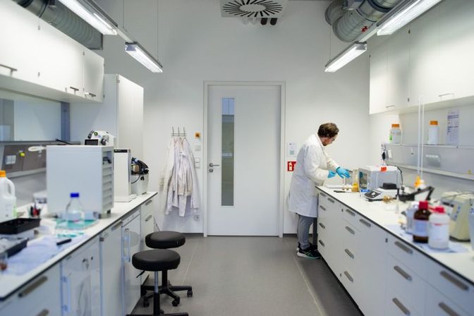 Scientist in a lab coat working at a bench in a bright laboratory