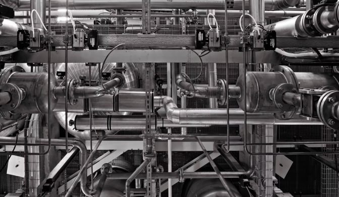 Stainless steel pipework and valves in an industrial plant, in black and white