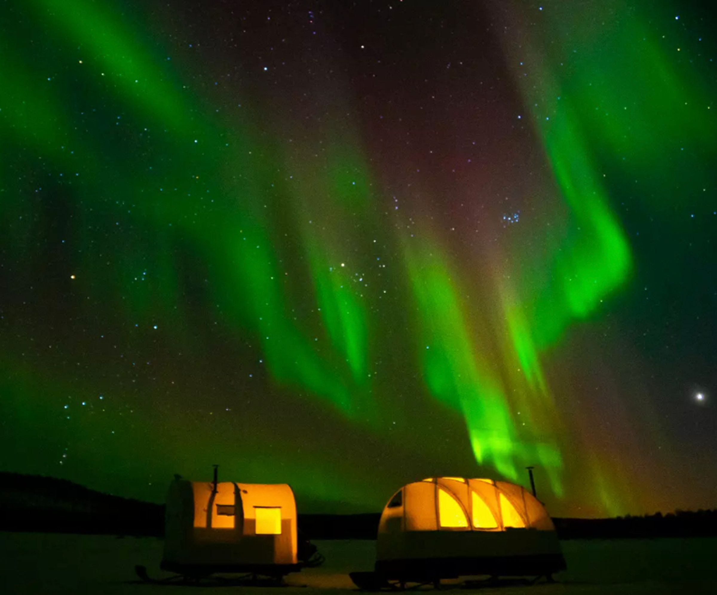 Northern lights behind a lighthouse accommodation in Senja, Norway