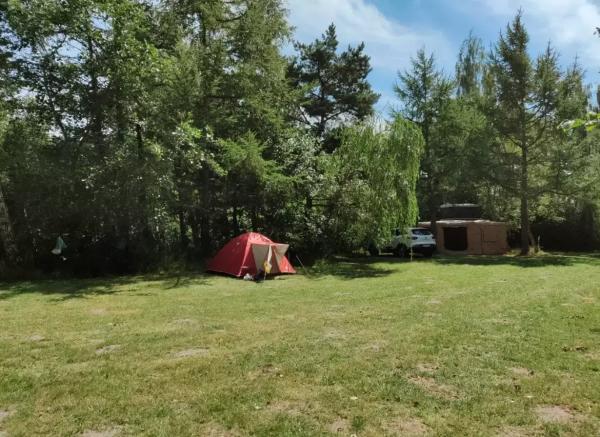 Et lite rødt telt på en liten og autentisk teltplass midt i naturen.