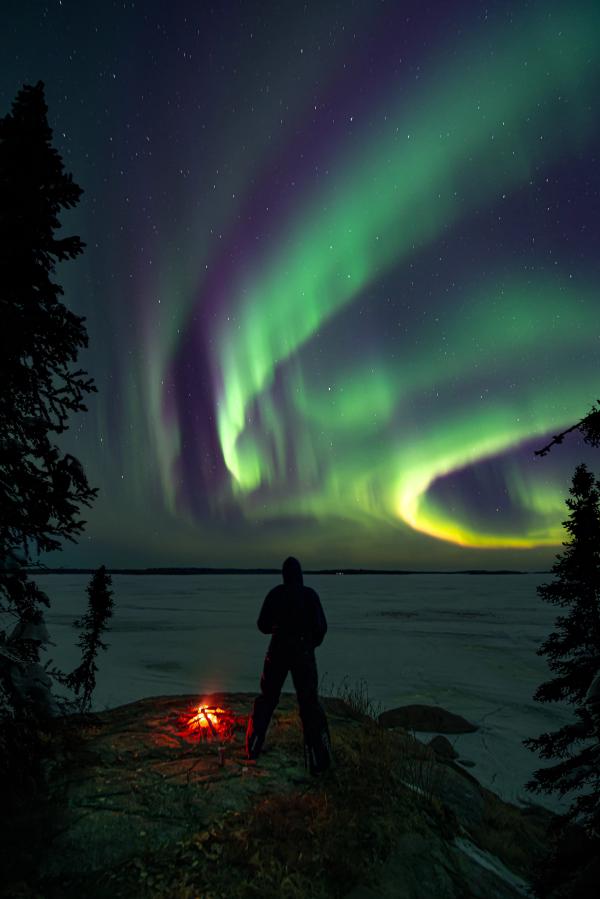 Guy looking out at northern light from a viewpont with a fireplace