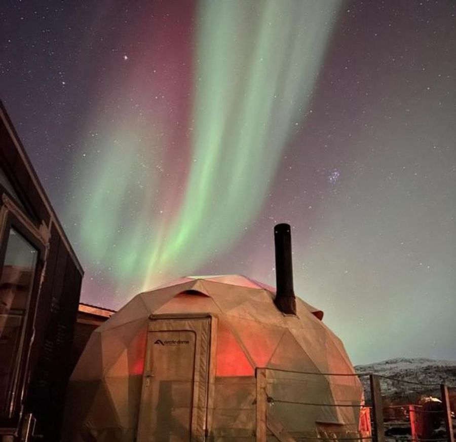Stjernehimmel og nordlys bak domen og mikrohuset utenfor Tromsø