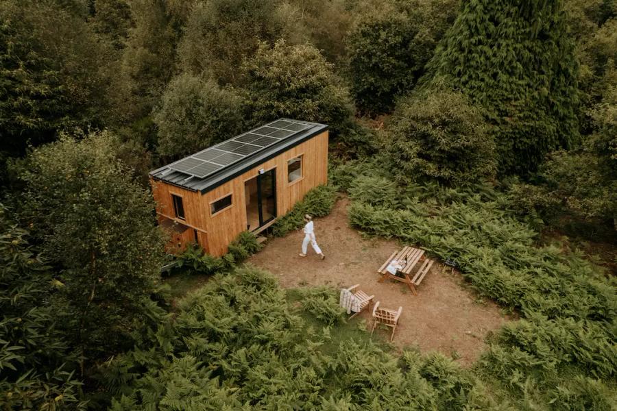 Uma pequena casa no campo em França, com telhado de telhas escuras, rodeada por árvores e um jardim