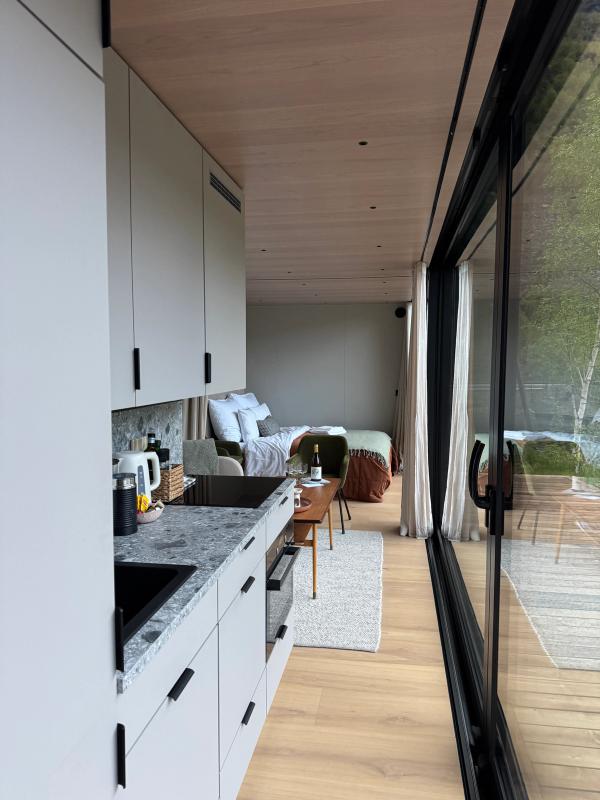 Minihuset på Flåm Retreat omgitt av frodig vårnatur