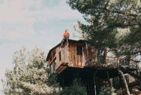 Ein Junge sitzt auf dem Dach eines Baumhauses