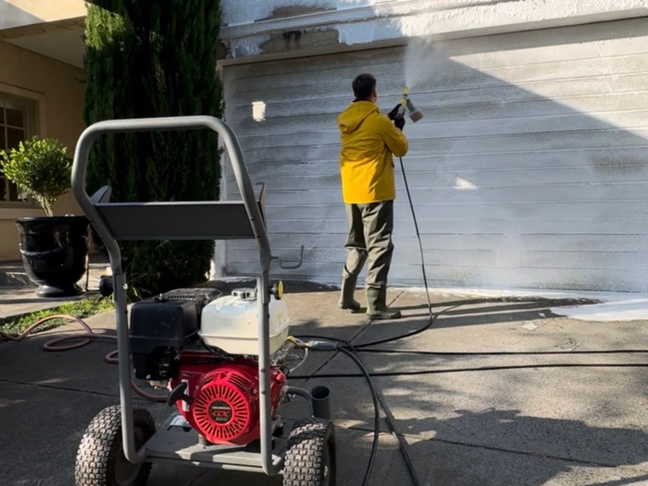 WaterCrew technician applying a low-pressure soft wash to a rendered wall