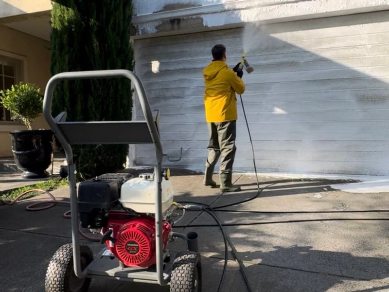 WaterCrew technician applying a low-pressure soft wash to a rendered wall
