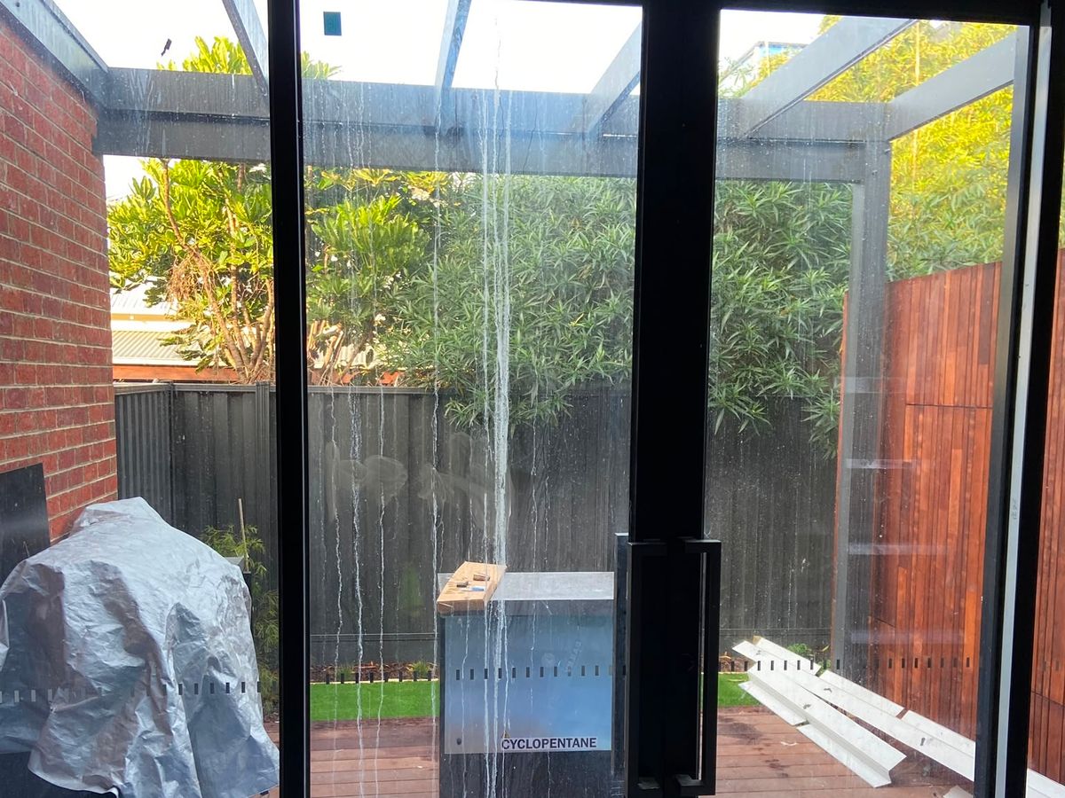 White mineral streaks running the full height of new sliding glazing on Yarra Street, Abbotsford