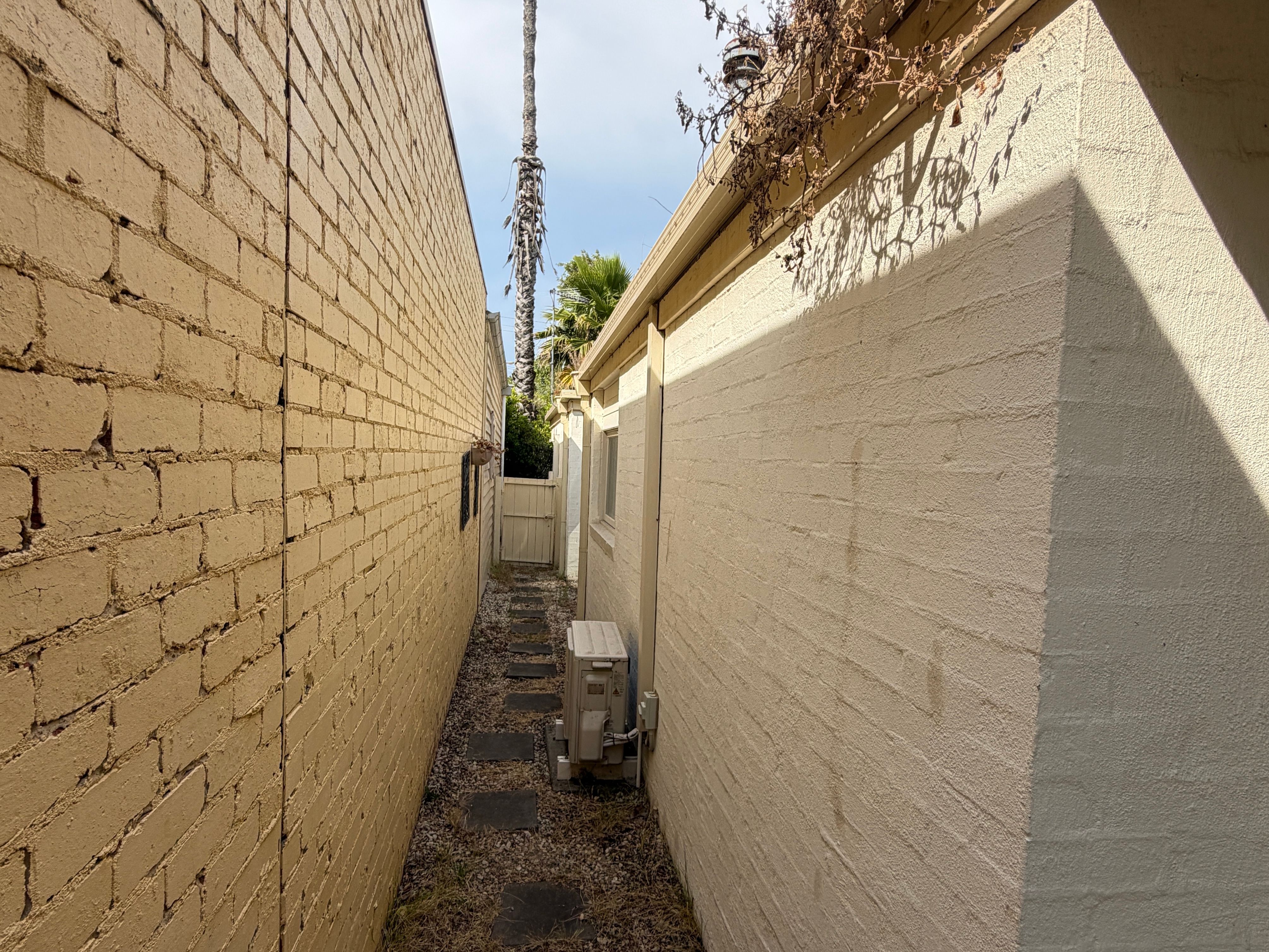 Painted brick and rendered walls in a narrow Brighton side passage, mortar joints visible