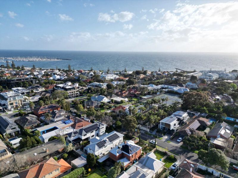 Aerial over Hampton rooftops and solar panels with the bay and a marina on the horizon