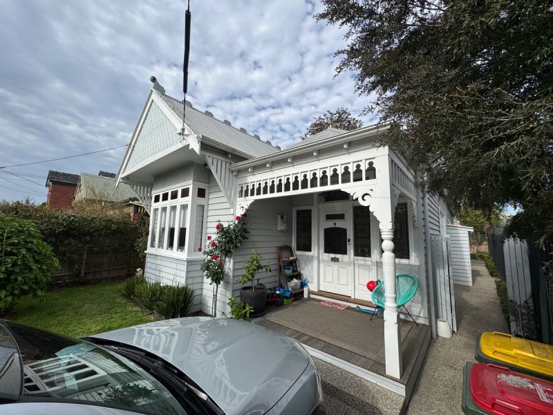 White weatherboard cottage in St Kilda East with timber fretwork on the verandah