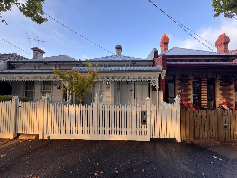 Victorian frontage on Richardson Street, Albert Park, with cast-iron lacework, an iron roof and a white picket fence