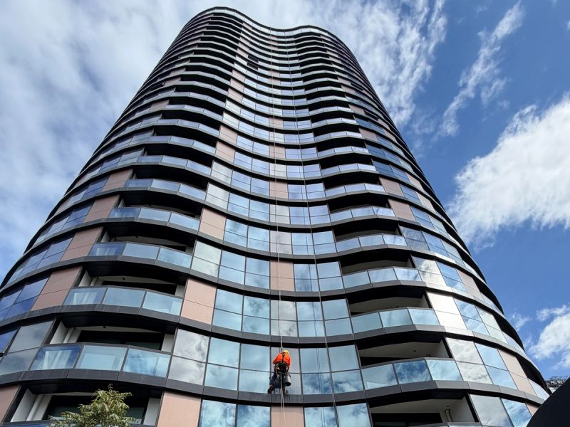 Rope access technician part way down a curved apartment tower on Gladstone Street, South Melbourne