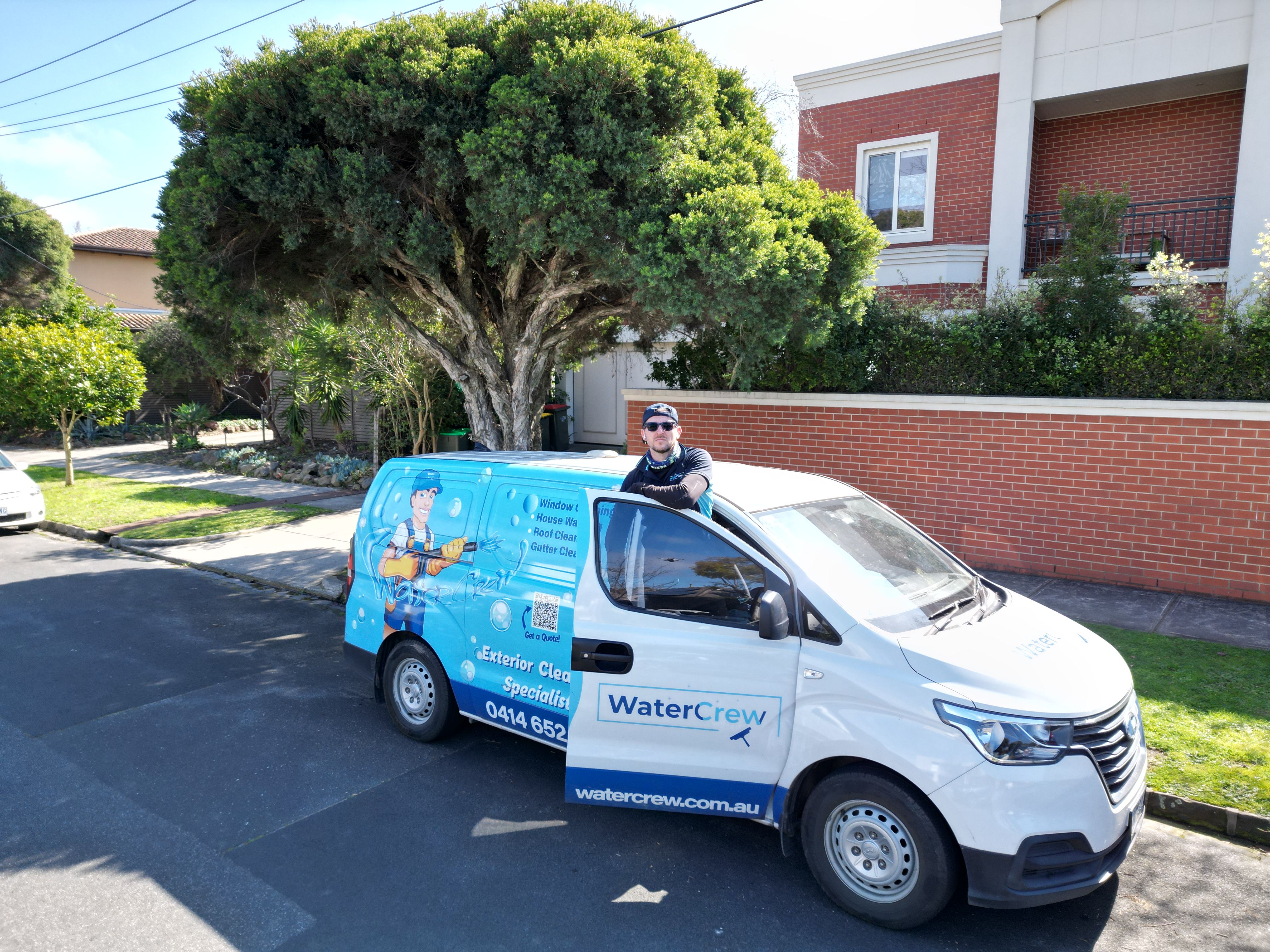 Technician at the WaterCrew van outside a two-storey red brick home in Caulfield North